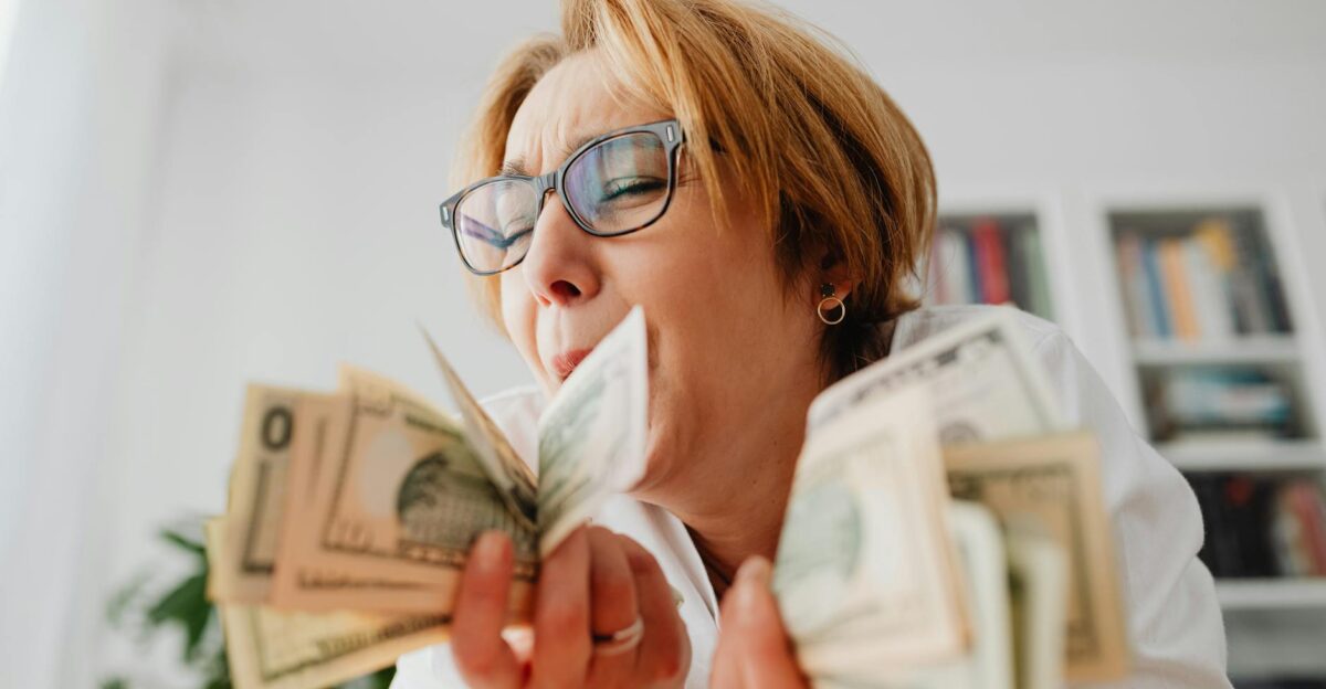 A happy woman with eyeglasses cherishing US dollar bills indoors symbolizing wealth and financial success
