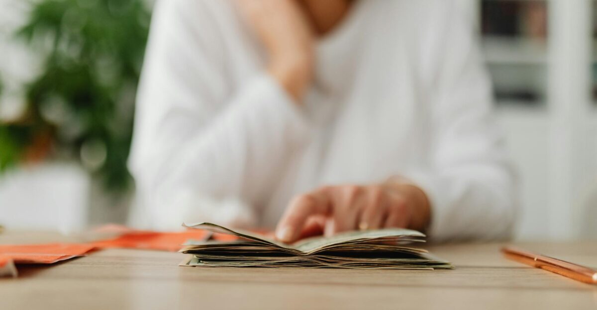 A woman sitting at a desk sorting through cash focusing on household budgeting