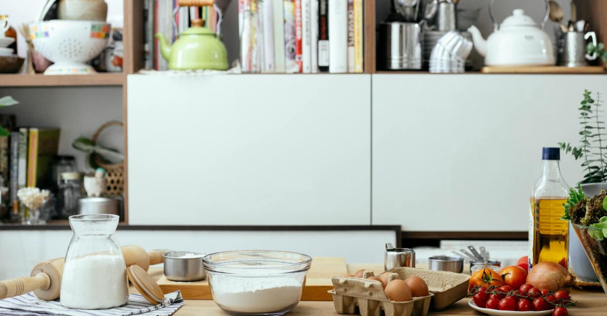Bowl of flour and eggs on table with and tomatoes and olive oil in contemporary light kitchen