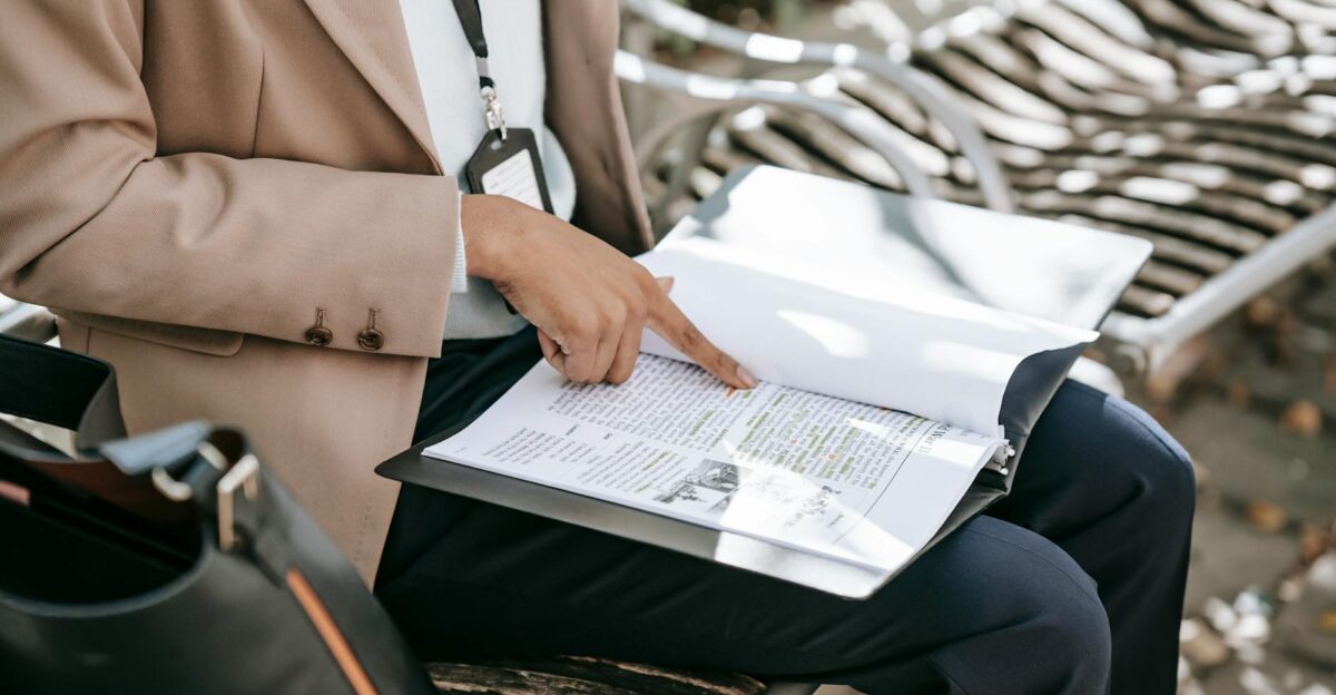 A woman reviewing documents on a park bench during daytime focusing on work or study