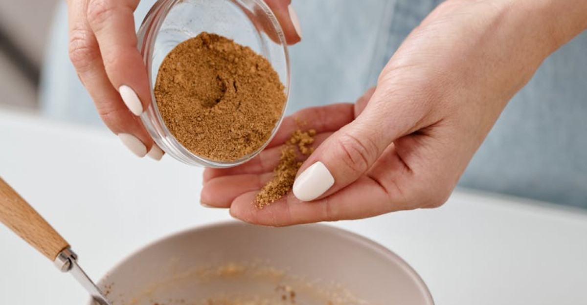 Close-up of hands adding cinnamon to a homemade baking mix in a modern kitchen setting