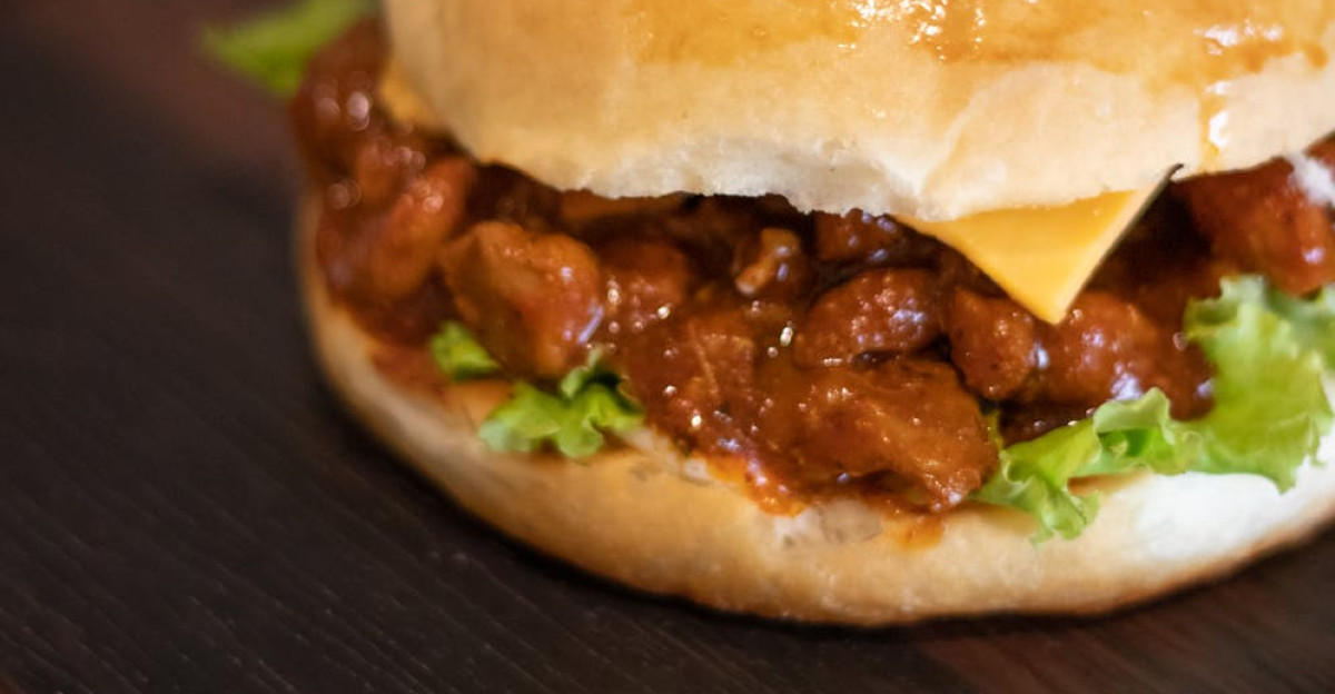 Close-up of a juicy sloppy joe burger with cheese and lettuce on a wooden board perfect for comfort food lovers