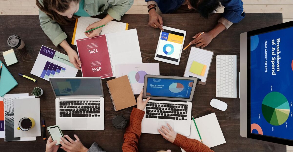 A diverse team collaborating on digital marketing strategies at a desk using laptops and tablets