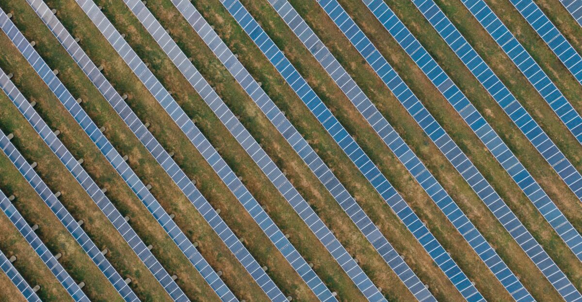 Aerial view of uniform solar panels in a green field showcasing sustainable energy