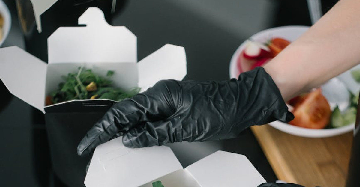 Gloved hands preparing fresh salad takeout in eco-friendly containers for delivery