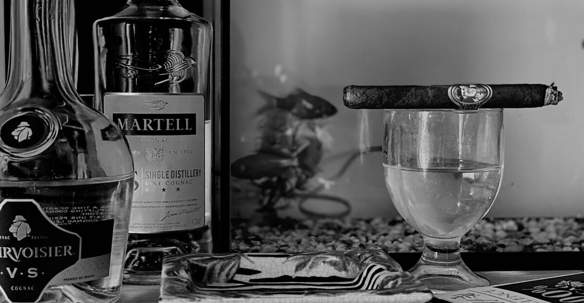 Monochrome still life featuring cognac bottles a cigar and glassware offering elegance and sophistication