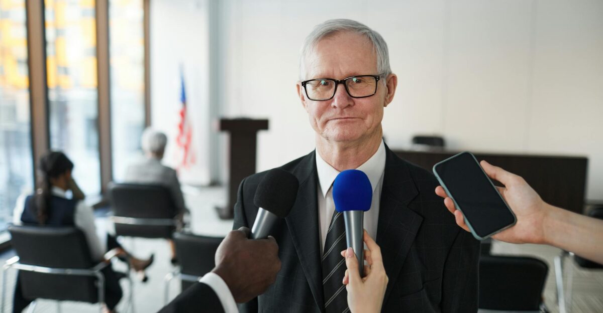 Senior man in formal attire being interviewed in a conference room