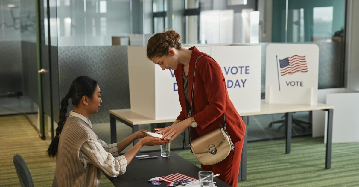 Two women interacting at a registration desk on election day indoors
