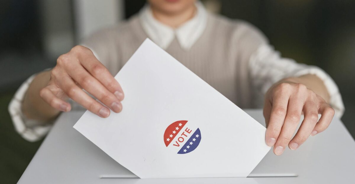 A person casting a vote by placing a ballot into a ballot box symbolizing democratic participation
