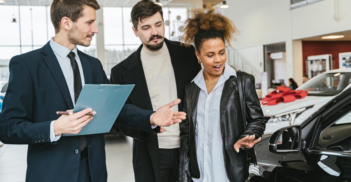 A diverse group of adults discussing vehicles at a bright modern car dealership