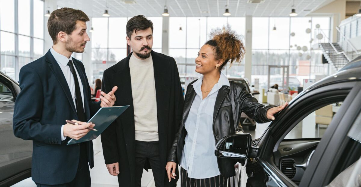 A diverse team of adults discussing a car purchase in a dealership showroom