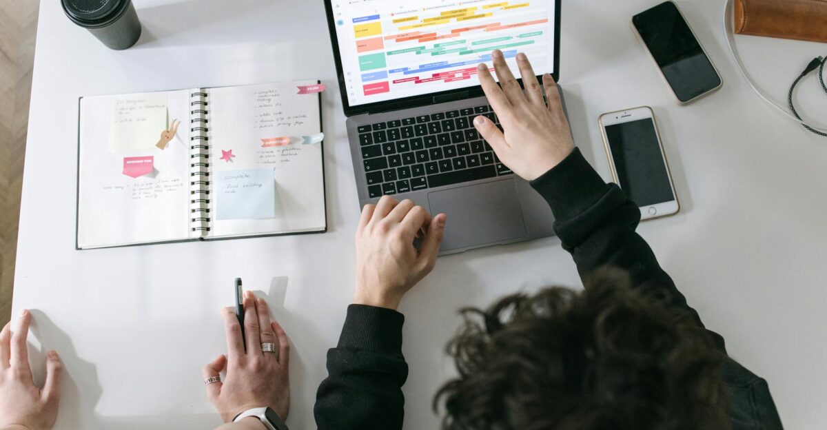 Two people collaborating on a laptop and planner at a vibrant modern office desk