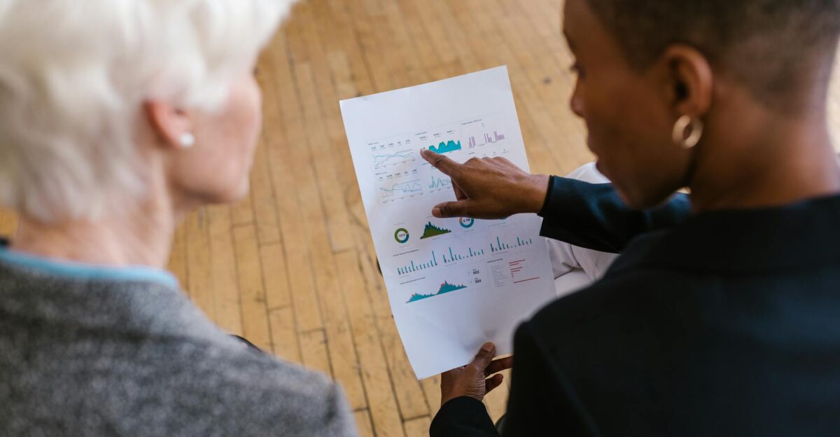 Two professionals reviewing business documents with graphs in an office setting