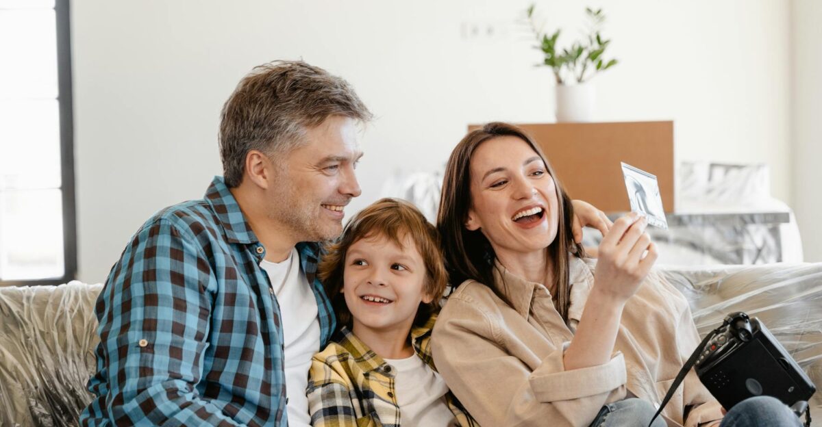 A cheerful family enjoys time together on a couch surrounded by moving boxes in their new home