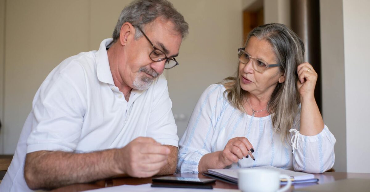 Senior couple reviewing documents and managing finances together at home showing collaboration and care