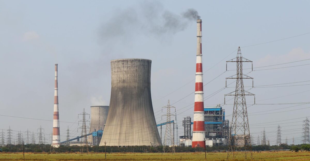 Smokestacks and a cooling tower emit smoke at a power plant in Vijayawada India