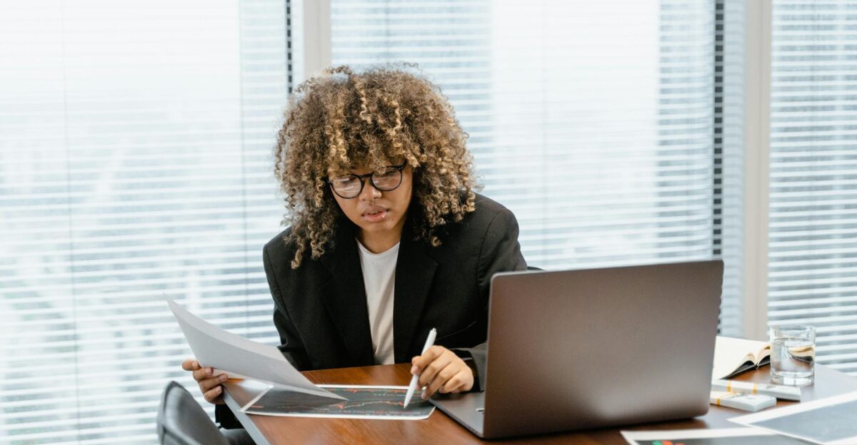 A young professional analyzing financial charts at a modern office desk with a laptop
