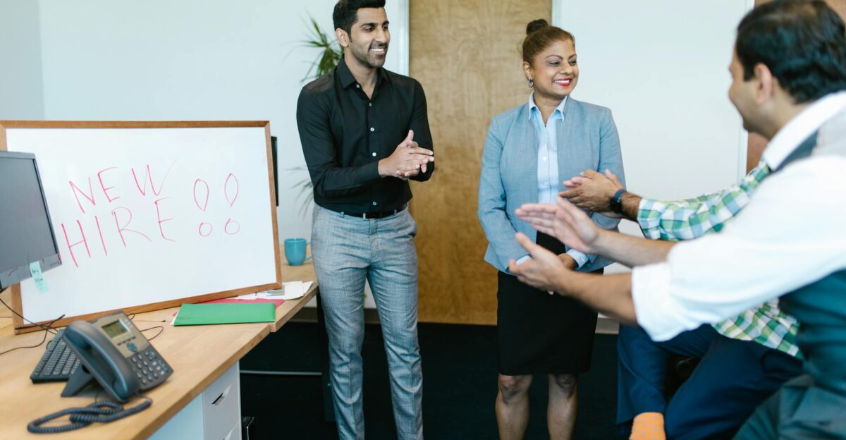 Colleagues joyfully applaud a new hire announcement in a modern office setting
