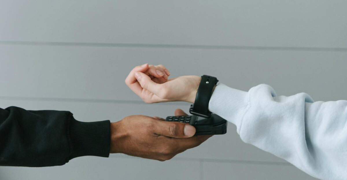 A person using a smartwatch for a secure contactless payment on a portable terminal indoors