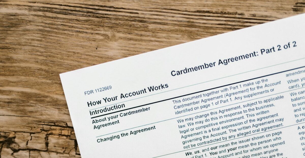 Close-up of a credit card agreement document on a textured wooden desk