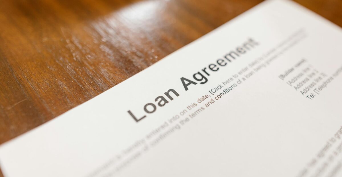 Detailed loan agreement document close-up on a wooden table representing legal and financial concepts