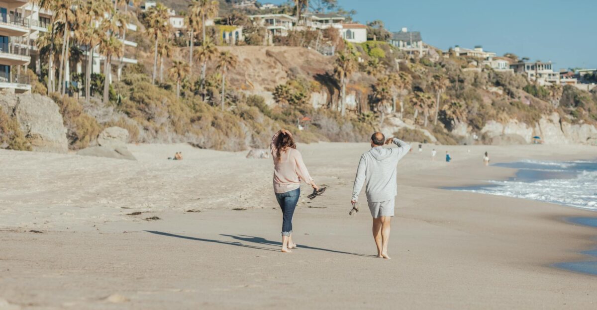 Mature couple walking along a sunny beach enjoying the ocean breeze and scenic view