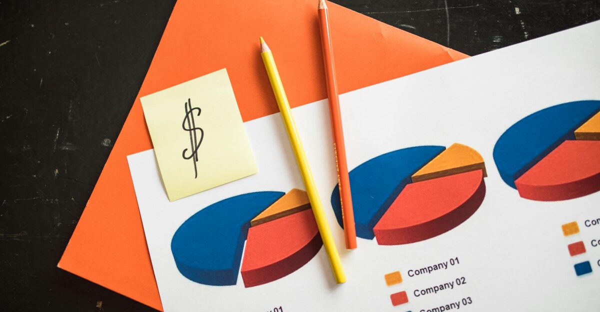 A creative arrangement of financial pie charts with colorful pencils and a dollar note perfect for business themes