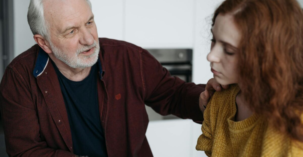 An elderly man consoles a young woman indoors expressing empathy and understanding