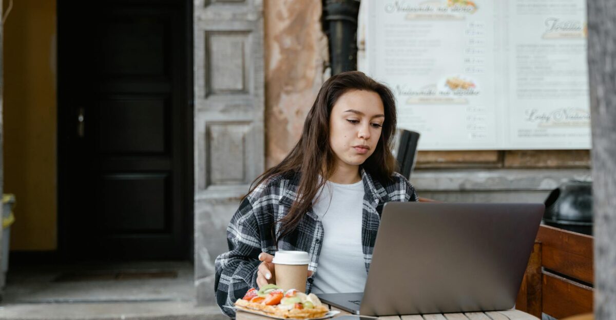 Woman working remotely on a laptop sitting at an outdoor caf with coffee and snacks