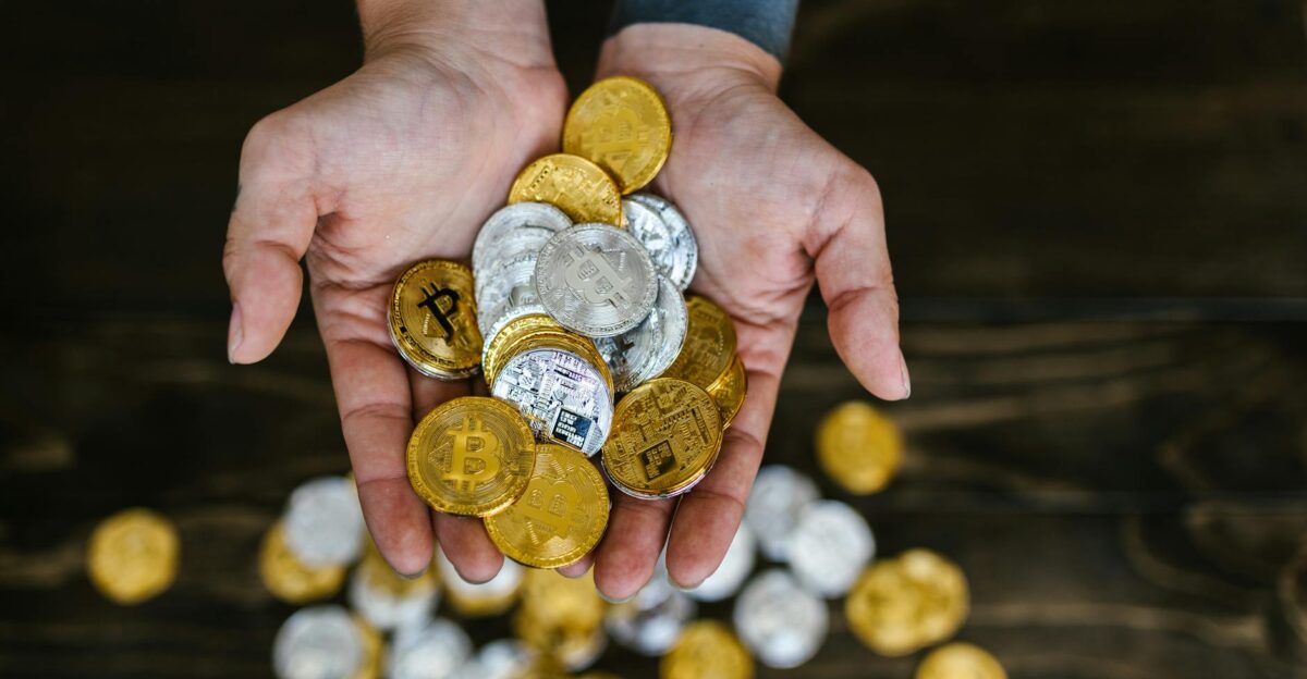 High angle of hands holding gold and silver cryptocurrency coins symbolizing digital wealth