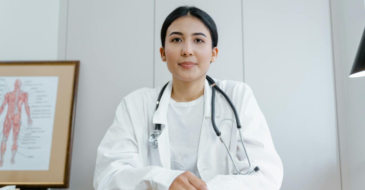 A female doctor confidently sits at her desk ready for consultation in a medical office