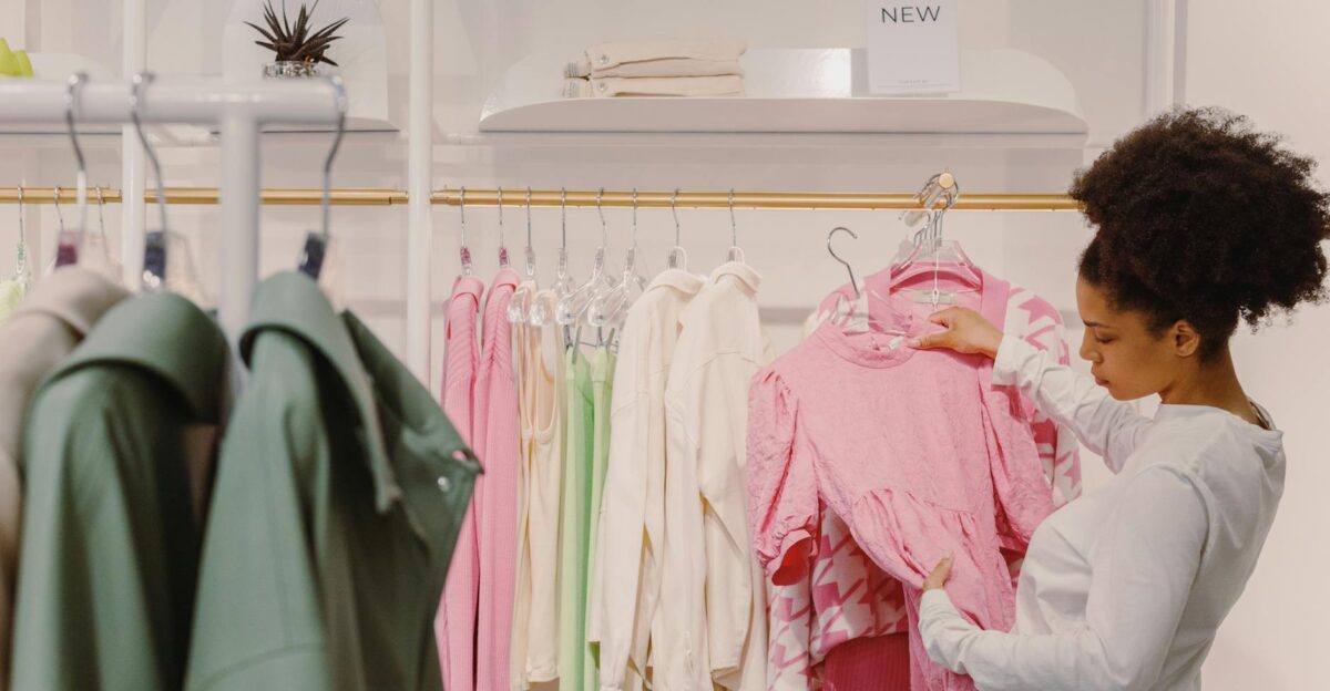 A stylish woman explores pink and pastel outfits in a modern boutique