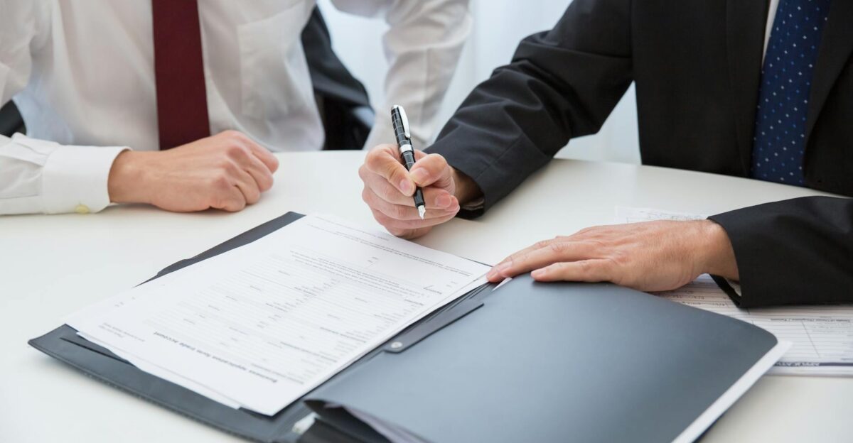 Two professionals signing a contract at a business meeting in an office