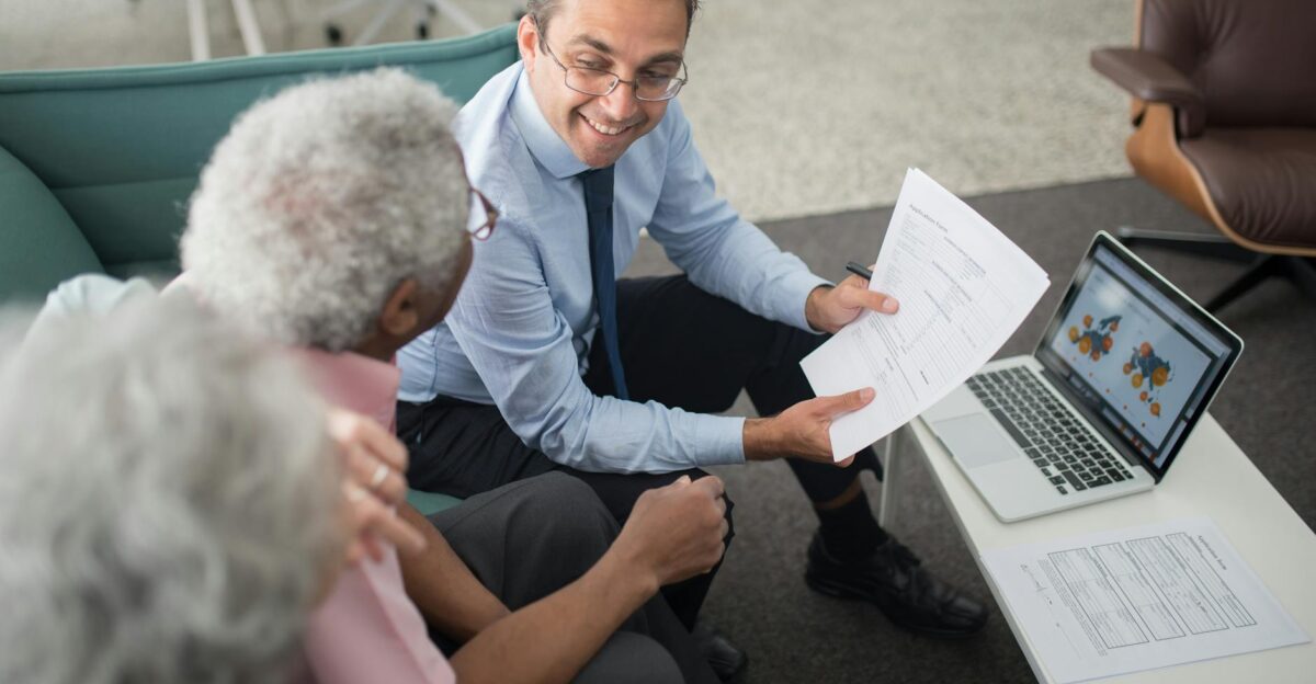 Financial advisor discussing documents with senior clients in an office setting showcasing a collaborative consulting session