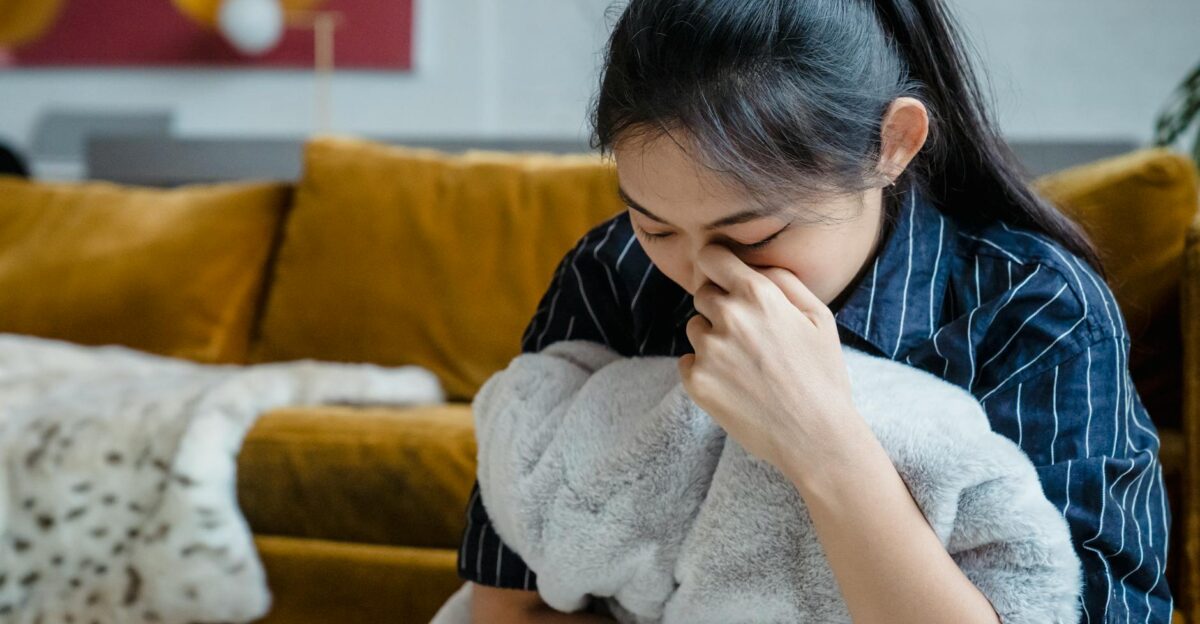 A woman sitting indoors holding a blanket conveying emotions of stress and contemplation