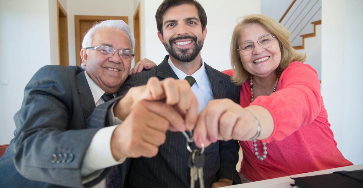 Smiling elderly couple receiving house keys from realtor indoors