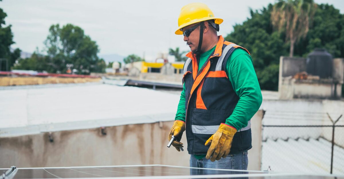 A solar technician in protective gear inspecting rooftop solar panels outdoors