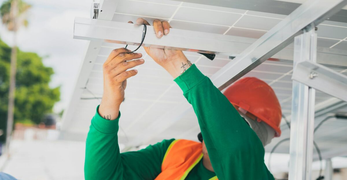 A solar technician in PPE installs a solar panel showcasing renewable energy work