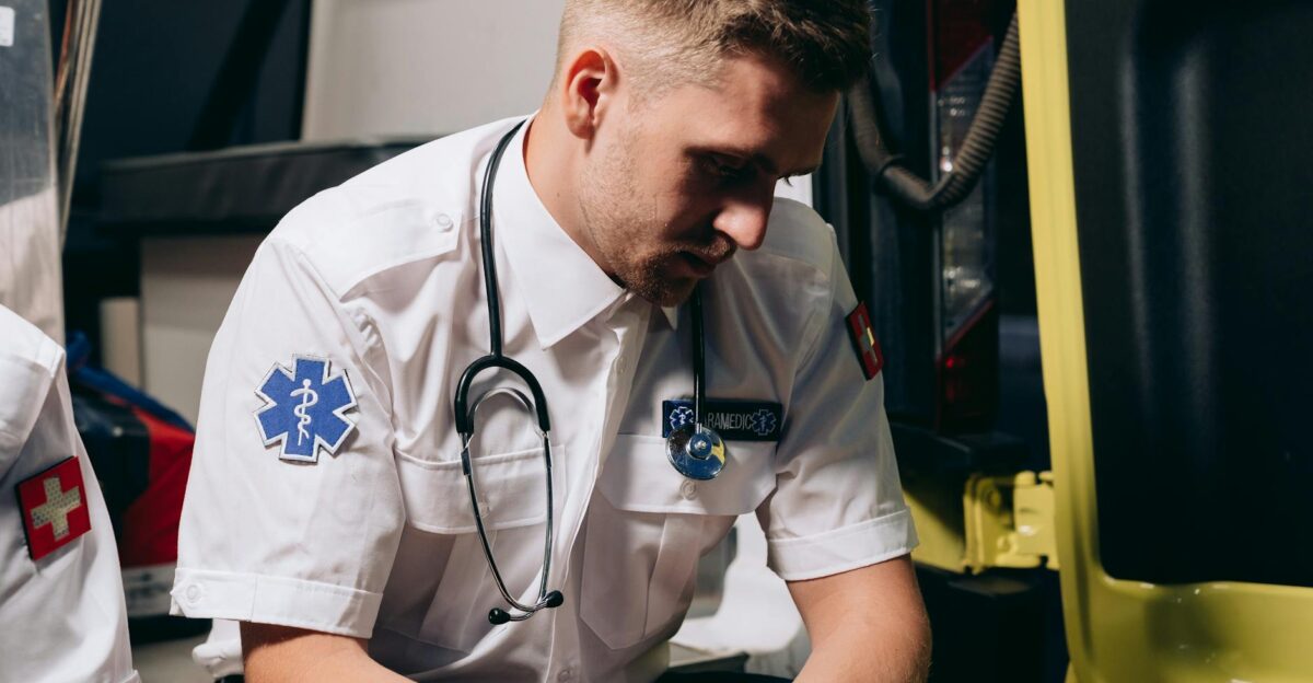 A paramedic in uniform sits pensively inside an ambulance conveying healthcare dedication