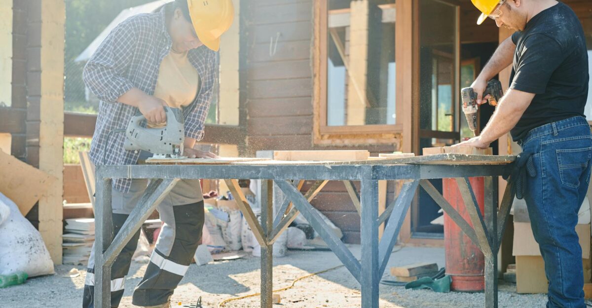 Two construction workers using power tools on a sunny day