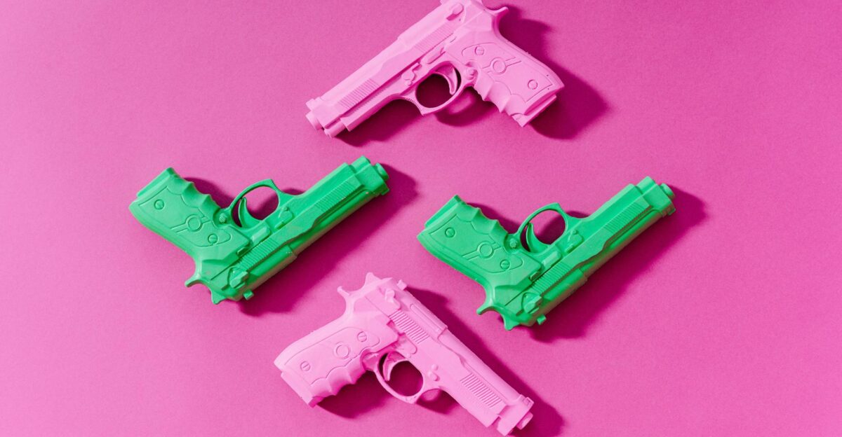 Top-down view of pink and green toy guns over a vibrant pink background
