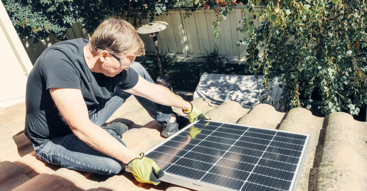 Male technician installing solar panel on roof promoting sustainable energy