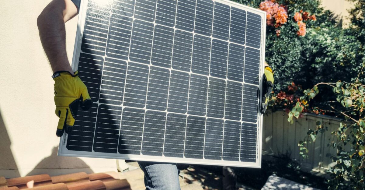 Technician carrying solar panel on rooftop Clean energy installation outdoors