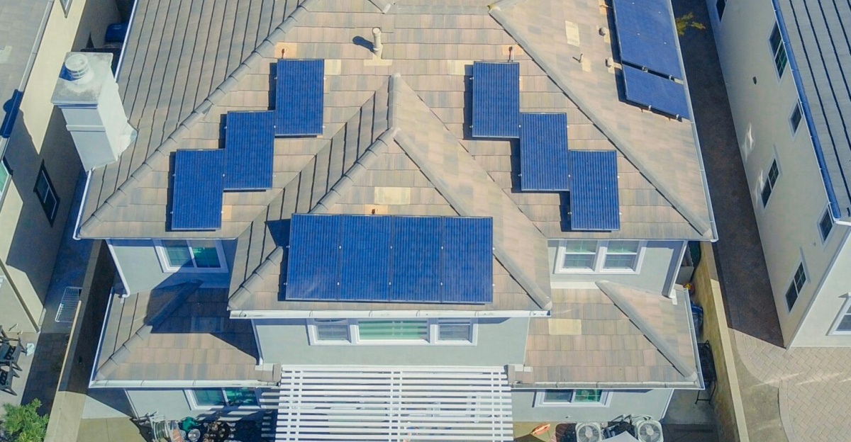 Aerial view of suburban homes equipped with solar panels in a sunny neighborhood.