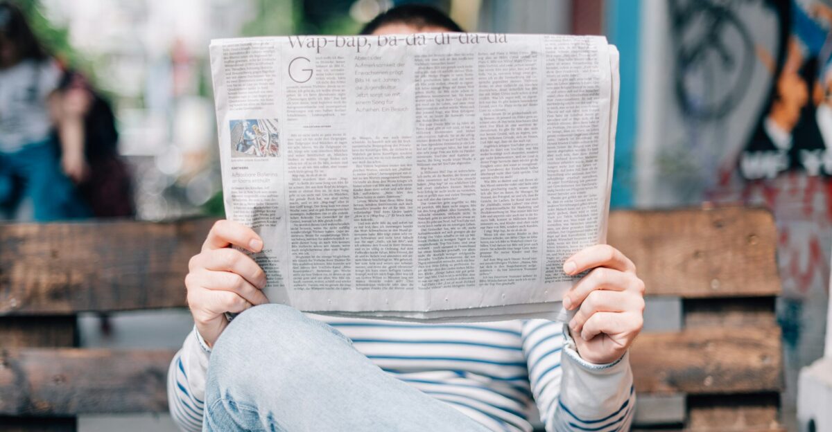 man sitting on bench reading newspaper