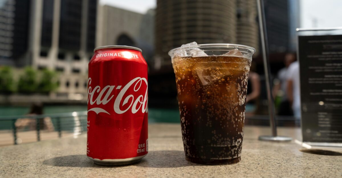 Coca-Cola soda tin can and cup on table close-up photography
