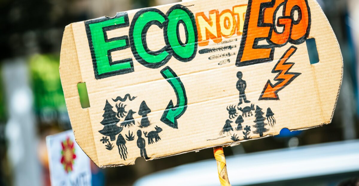 person holding Eco Not Ego signage