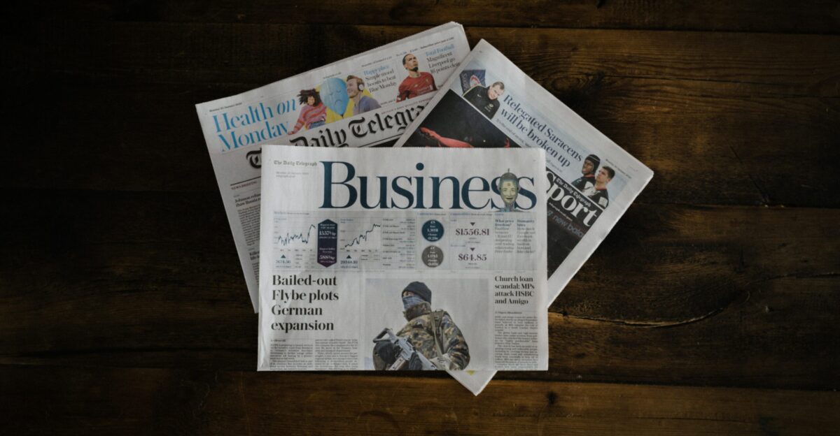 a stack of newspapers sitting on top of a wooden table