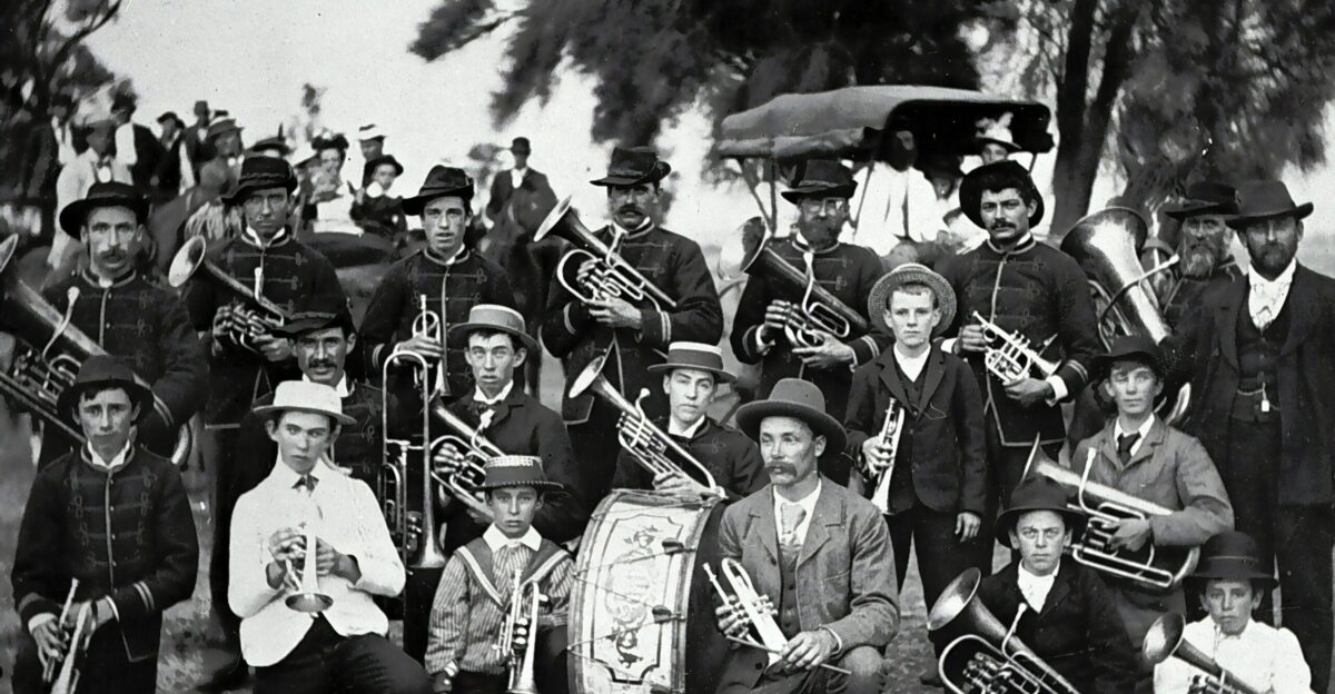 grayscale photo of men in black hat playing musical instrument