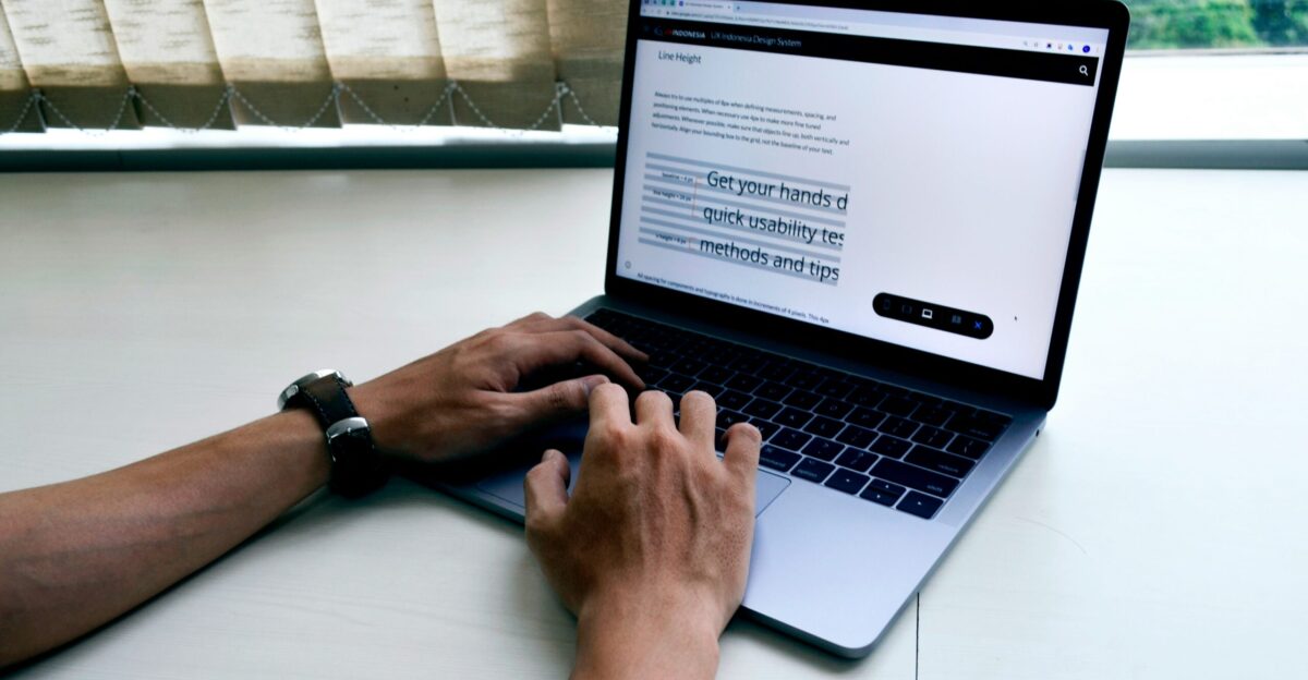 person using macbook pro on white table